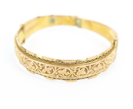 An early 20th century 9ct rose gold fancy half-hoop bangle. The front in the form of a floral chased scrolling panel between 