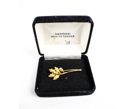 An early 20th century gold and bouton pearl brooch in the form of two oak leaves and acorns. Stamped '15ct', 3g gross