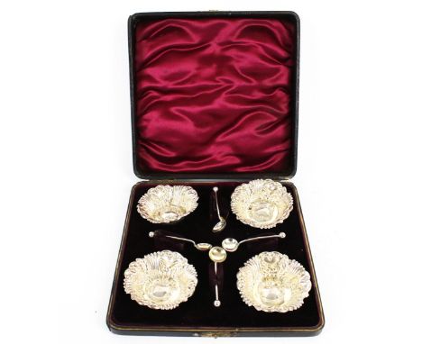 A set of four Edwardian silver small round salts and spoons. Each salt with a shaped rim and embossed with a vacant scroll ca