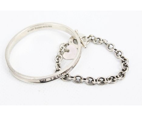 A fluted slave bangle stamped 'Tiffany &amp; Co .925' and a round belcher link bracelet with a heart pendant. The bangle meas