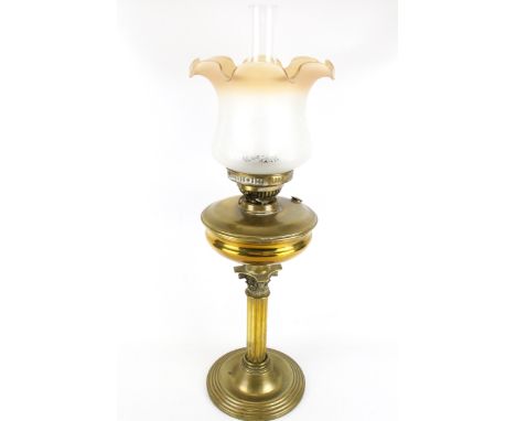 A brass oil lamp with shade and chimney. Circa 1900, the gilt brass reeded Corinthian column on a circular base, with twin bu
