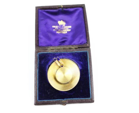An early 20th century gold and blue enamel brooch in the form of a straw 'boater'. The engine-turned hat with a slightly rais