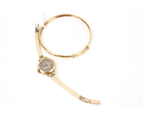 A modern 9ct gold bangle and a lady's 9ct gold cased wrist watch. The bangle with a textured finish and post 2000 laser conve