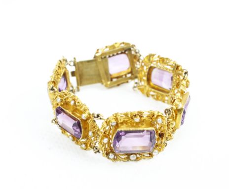 An early 20th century gold and amethyst six stone floral panel bracelet. With pearl accents in the early Victorian cannetille