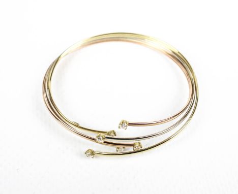 A 9ct tri-colour gold and cubic zirconia bangle. In the form of three cross-over wire hoops with cz terminals, stamped '9ct' 