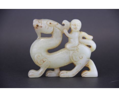 A Chinese 19th / 20th Century mutton fat and russet jade figure of a boy riding a dragon, H. 8.3cm, L. 10cm.