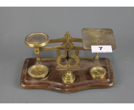 A Post Office scale and weights on a wooden base, W. 19cm, H. 8cm.