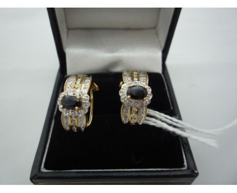 A PAIR OF SAPPHIRE AND DIAMOND EARRINGS, with oval sapphire, diamond scalloped surround and tri-line border