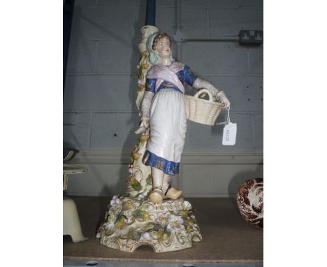 A CONTINENTAL CENTREPIECE/CANDLESTICK, Dutch Woman with basket and fish, floral and vine encrusted base and candlestick, impr