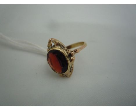 AN EARLY 20TH CENTURY GARNET RING, with faceted oval shape garnet with foliage surround, ring size O