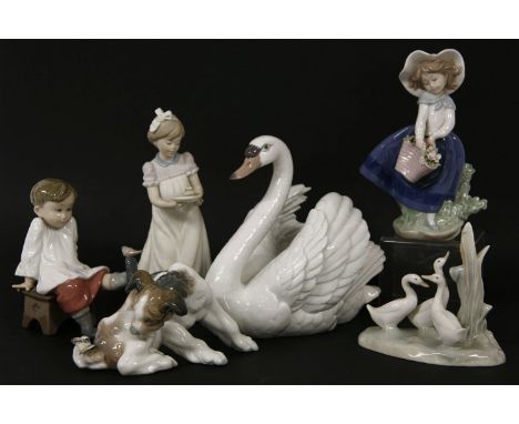 A Lladro swan together with a figure of a boy seated on a stool with a bird on his foot, a gaggle of geese, etc, the swan is 