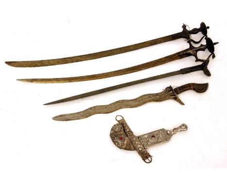 Two Indian Talwar swords, with carved blades, a Kris, a further sword with 'eared' wooden handle, and an Eastern white metal 