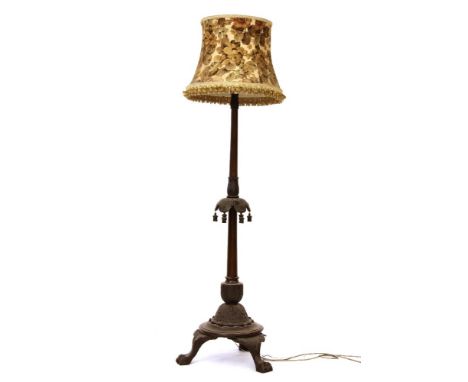 A carved beech wood standard lamp, with hanging tassels, on claw feet, with a shade, 187cm high