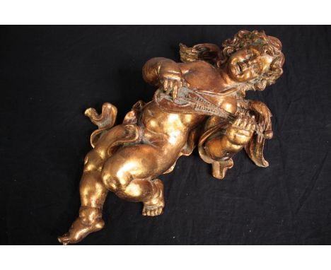 A plaster cherub playing a lute. Plaster finished in gold lacquer. H.50cm. 