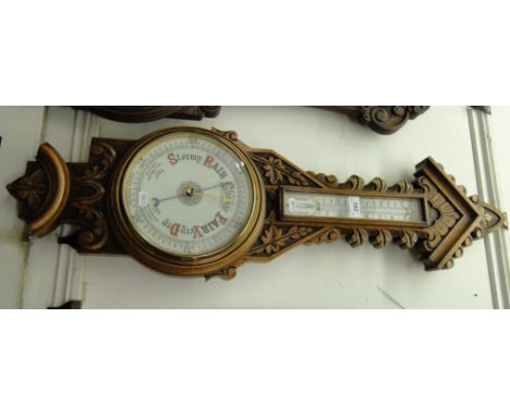 A carved oak cased aneroid barometer with thermometer.