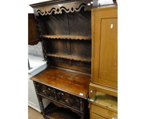 A 1920s narrow oak dresser, with open plate rack, cupboards and pot board under, bobbin turned legs.