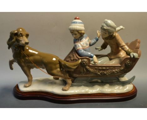 A large Lladro sleigh ride, model no.5037, dog and sleigh on wooden base, first quality, 23cm x 48cm, 1980