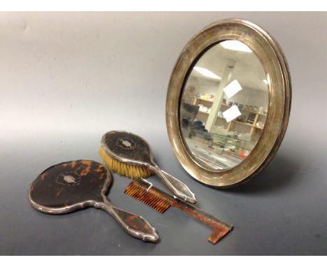 An Edwardian silver dressing table mirror, oval plate, Birmingham 1909;  a silver and tortoiseshell  hand mirror, brush and c