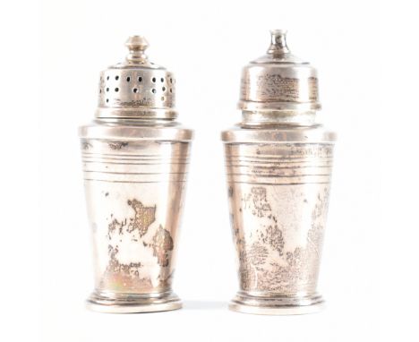 A pair of hallmarked silver salt &amp; pepper table condiments. The shakers raised on a stepped plinth base having a tapering