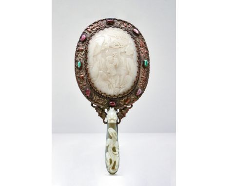 Ca. 18th century AD.A Chinese hand held mirror, with carved jade and bejeweled mount. The back of the mirror shows a scene of