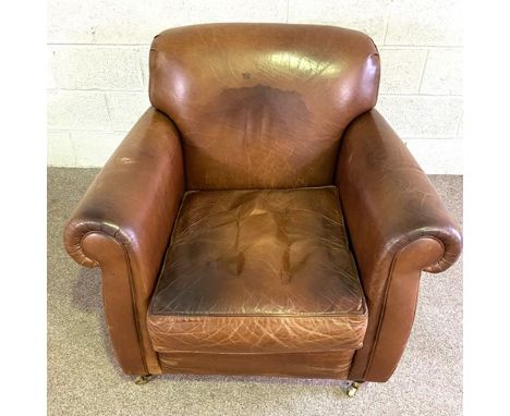 A large vintage leather armchair, 20th century, with deep back and scrolled arms, set on brass caps and castors