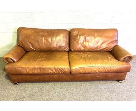 A vintage leather sofa, with long deep seat band brass hob-nailed scrolled ends, 230cm long