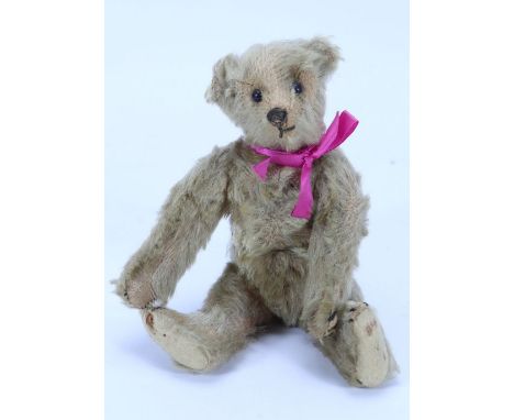 A small Steiff mohair Teddy bear, German circa 1909, the light brown straw stuffed bear with black boot button eyes, stitched