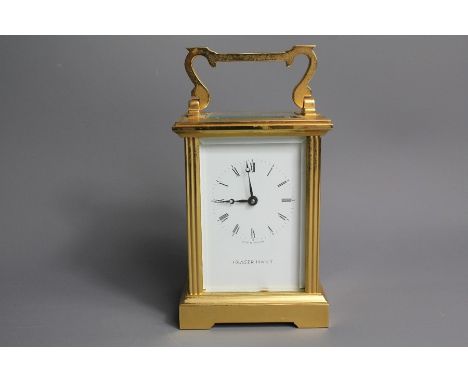 An English brass carriage clock, 7 jewel movement, retailed by Fraser Hart, white enamel face with Roman dial, approx 8 x 7 x