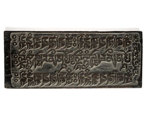 A CARVED WOOD BUDDHIST PRINTING BLOCK, TIBET, CIRCA 19TH CENTURY of rectangular form, with ebonised patina, with three revers