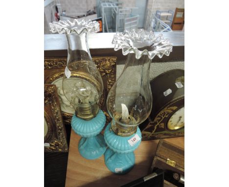 A pair of ceramic oil lamps with decorative glass chimneys