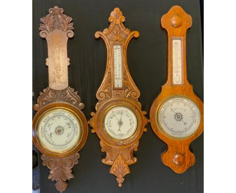 A carved oak framed aneroid barometer thermometer, cream registers, 72cm long;  others (3) 