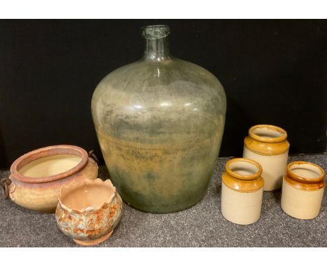 A large light green tinted glass Carboy;  pottery planters, stone ware jars etc 