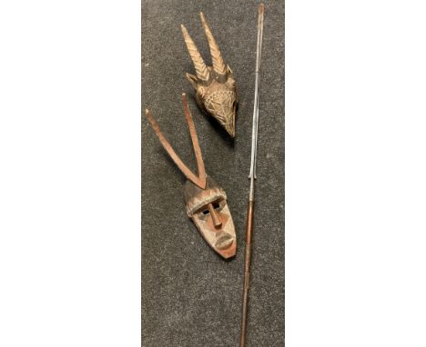 An East African hunting mask formed as a horned bird; another male face; an East African hunting spear, probably Maasai with 