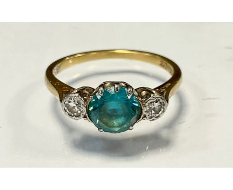 A diamond and vibrant blue stone ring, central vibrant pale blue round cut stone flanked by round brilliant cut diamonds, eac