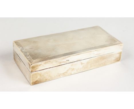 AN ENGINE TURNED SILVER CIGARETTE BOX. 7ins long.  Birmingham 1938.