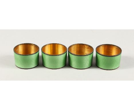 A SET OF FOUR SILVER AND GREEN ENAMEL CIRCULAR VODKA TOTS.
