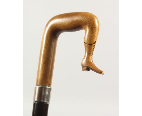 A 19TH CENTURY WALKING STICK, the handle as a carved wood ISLE OF MAN TYPE LEG with plain silver band. 3ft long.