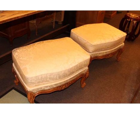 Pair Continental carved serpentine shaped footstools in light foliate pattern fabric
