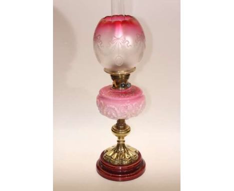 Victorian brass oil lamp with moulded opaque ruby tinted glass reservoir