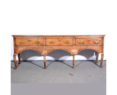 George II oak dresser base, basically 18th Century, boarded top, fitted with three deep drawers over three-arch apron, on nea
