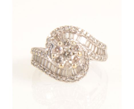 A diamond crossover cluster ring, a central cluster of seven brilliant cut diamonds claw set in an all white metal mount with