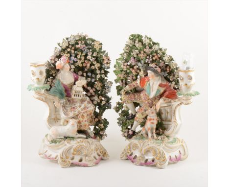 A pair of Derby bocage candlesticks, late 18th Century, modelled as a shepherdess with birdcage and lamb, and a young man wit