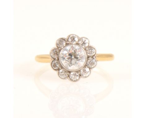 A diamond circular cluster ring, the central old brilliant cut diamond milgrain set and surrounded by ten smaller old cut dia