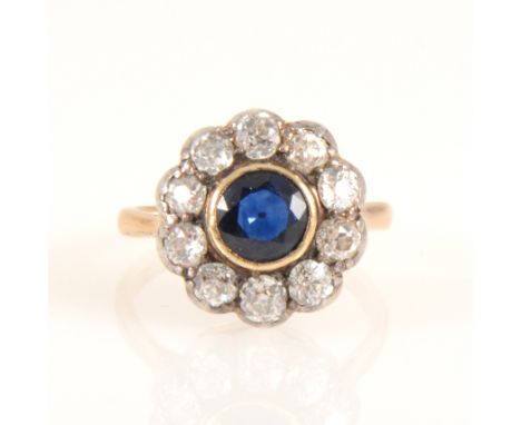 A sapphire and diamond circular cluster ring, the circular faceted sapphire 6mm diameter collet set and surrounded by ten old