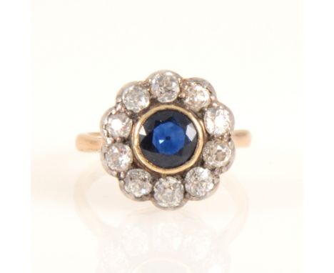 A sapphire and diamond circular cluster ring, the circular faceted sapphire 6mm diameter collet set and surrounded by ten old