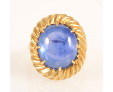 A sapphire dress ring, the oval cabochon cut sapphire 15mm x 13.5mm x 8mm claw set in an all yellow metal mount, spiral flute