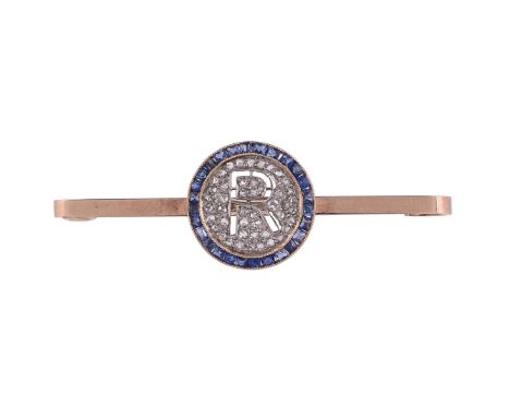 A SAPPHIRE AND DIAMOND INITIALLED PANEL BAR BROOCH The circular panel with a pierced R within a pavé set rose cut diamond sur