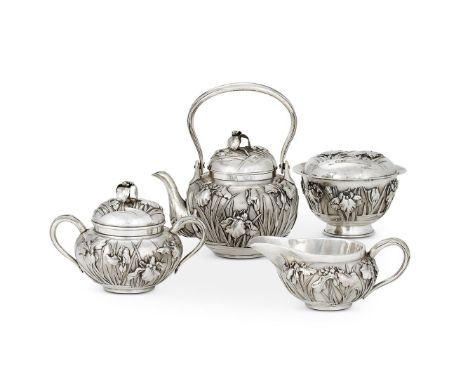 A JAPANESE SILVER THREE PIECE TEA SETEARLY 20TH CENTURYThe tea pot with a swing loop handle, the cover with an iris finial to