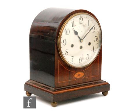 An Edwardian line inlaid mahogany domed mantle clock, with eight day striking movement, circular silvered dial on stepped bas