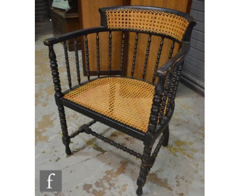 An Arts and Crafts ebonised armchair, with bergere canework back panel and seat and with turned spindles and stretcher frame.